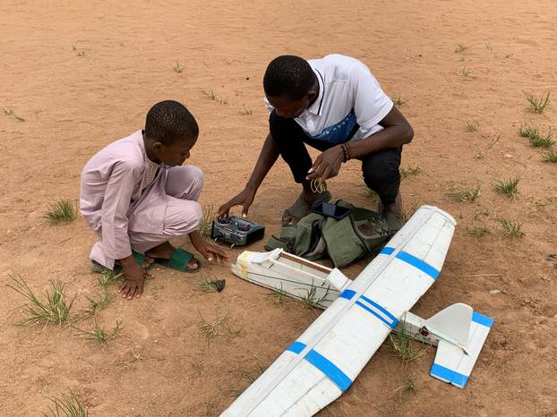 Bolaji Fatai and his apprentice, Jubril Abdullahi, prepare to fly a model aeroplane made from discarded waste, in Lagos