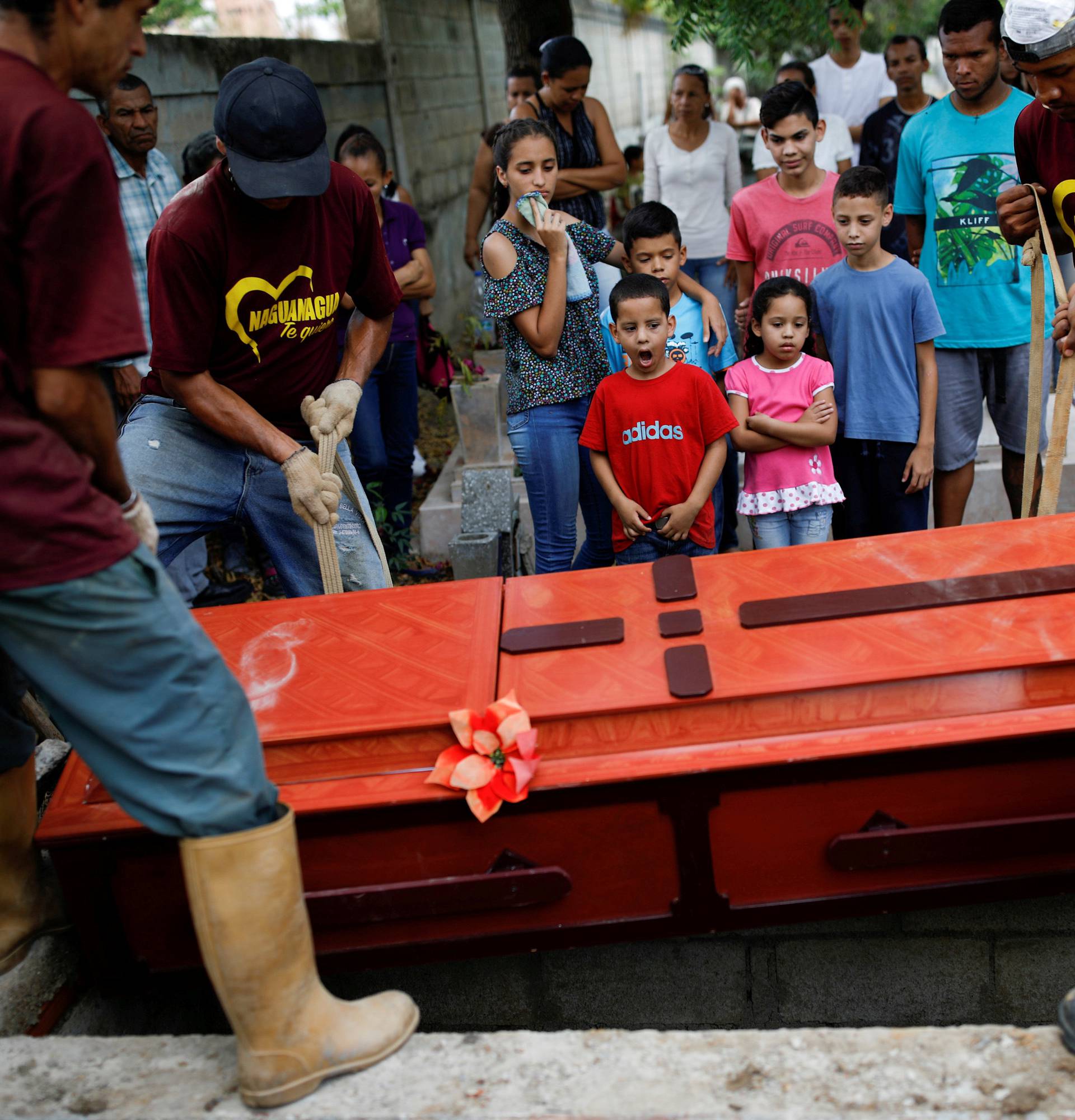 Relatives of Javier Rivas, one of the inmates who died during a riot and fire in the cells of the General Command of the Carabobo Police, react in front of his coffin during his funeral in Valencia