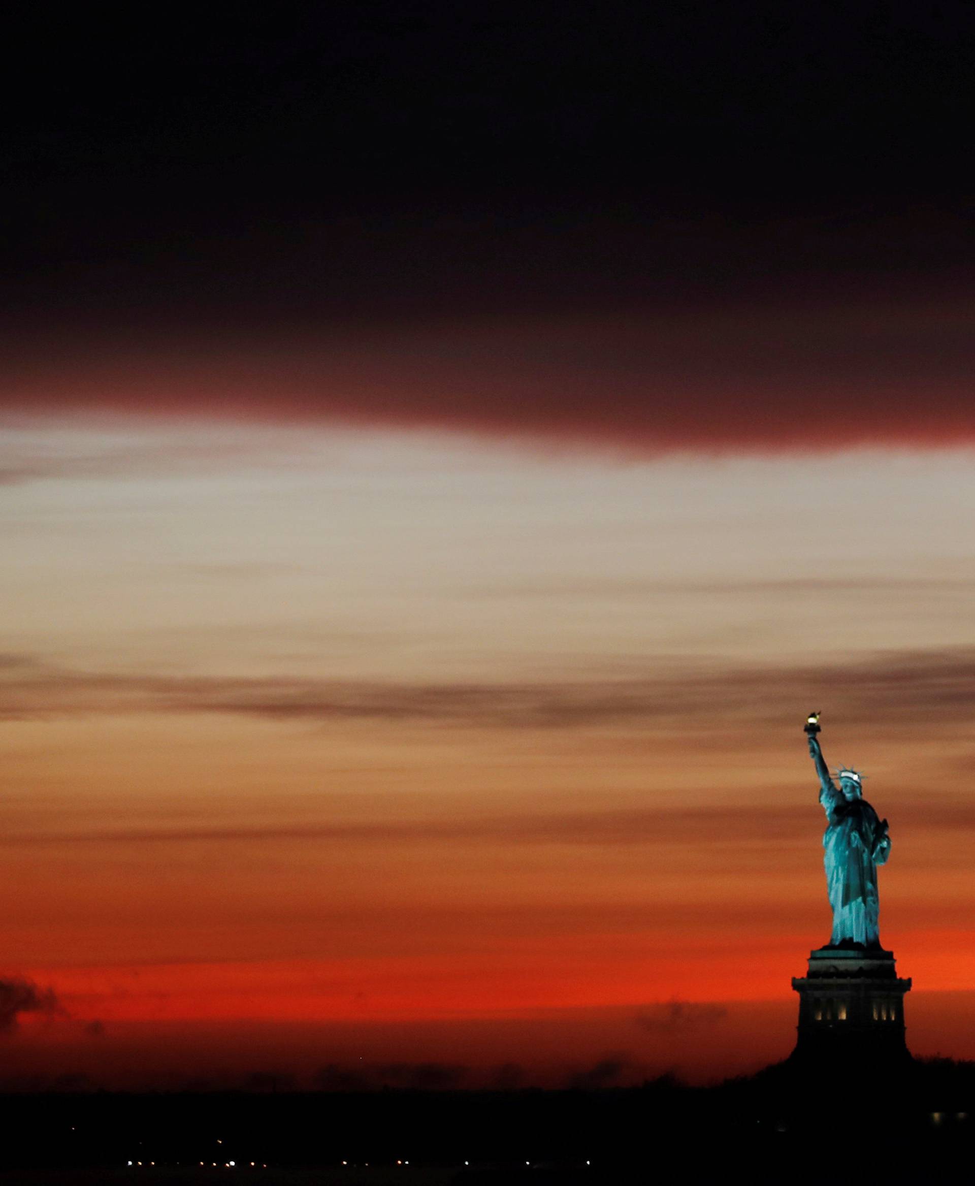 The sun sets behind the Statue of Liberty after a rain storm in New York