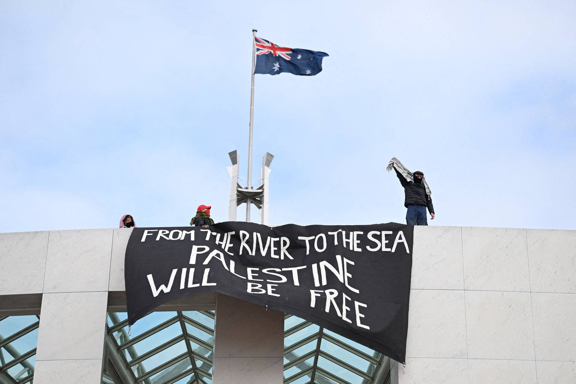 Pro-Palestinian protesters hang banners from the top of Parliament House in Canberra