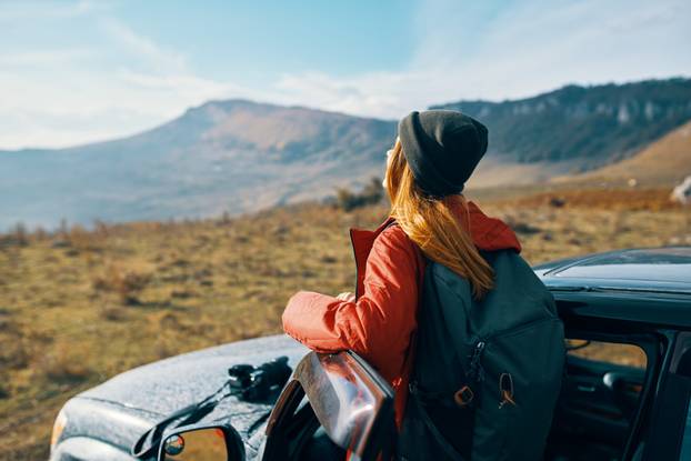 Traveler with a backpack near the car in the mountains in summer and Blue Sky Fresh Air