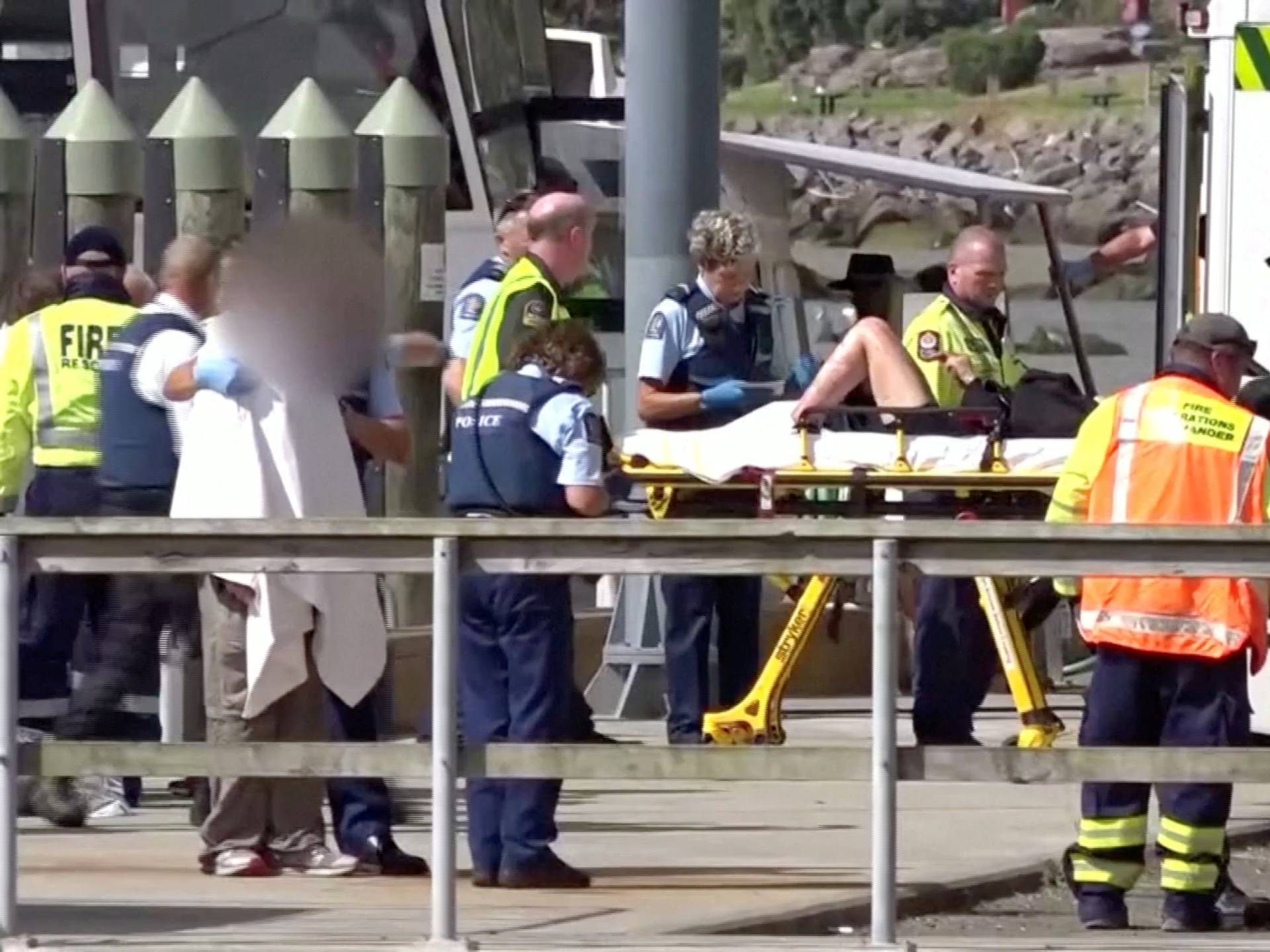 A person injured by the White Island volcano eruption is wheeled into a waiting ambulance on a stretcher in Whakatane