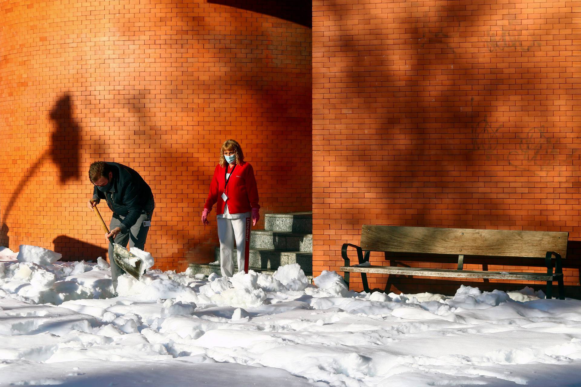A worker shovels snow from the entrance of a building after heavy snowfall in Madrid
