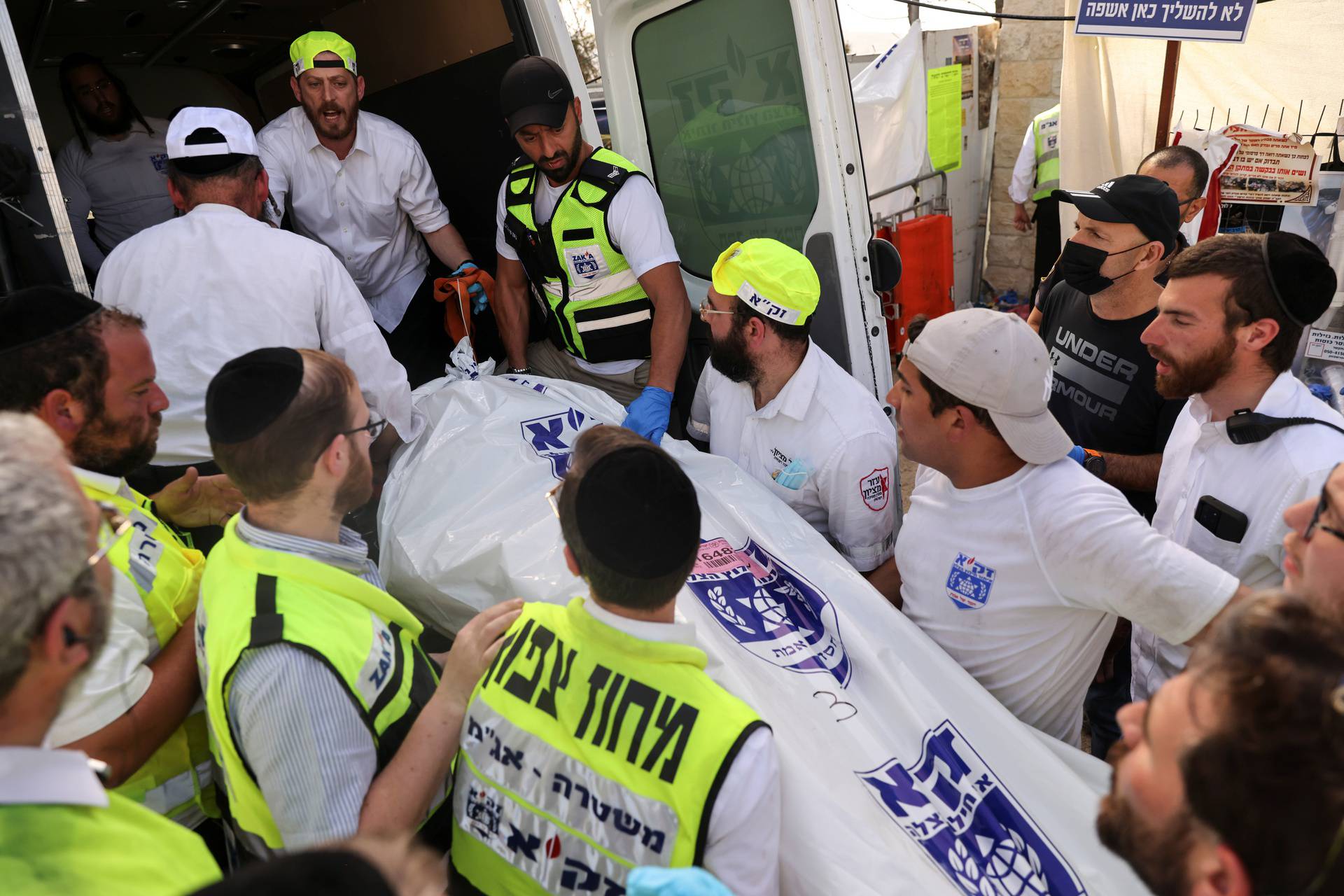 Rescue workers take a dead body into an ambulance on Mount Meron