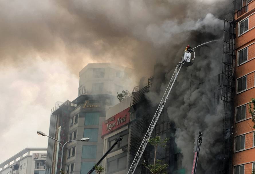 Firefighters work after a fire broke out at a karaoke lounge in Hanoi