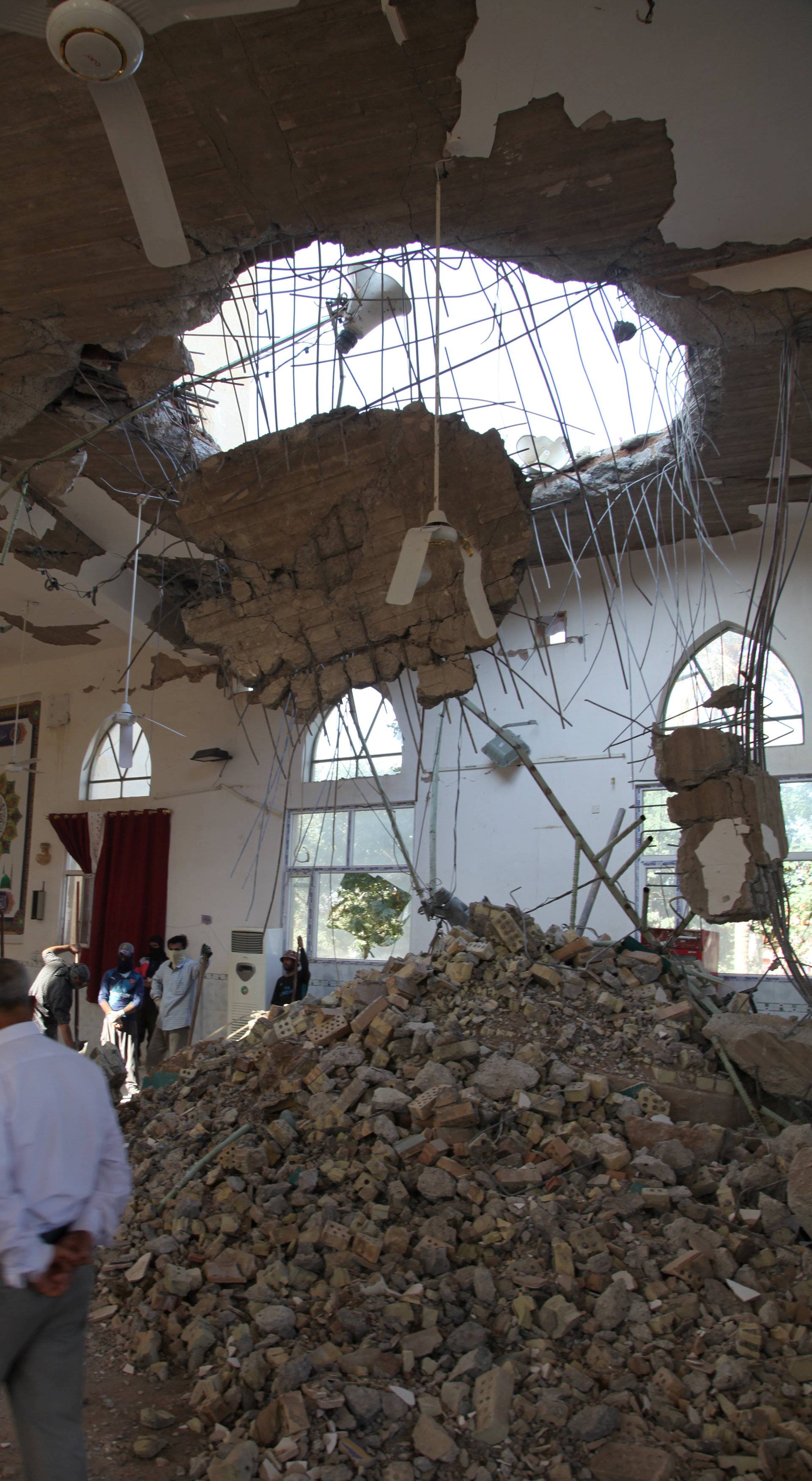 People remove rubble from a damaged mosque following an earthquake in Khanaqin