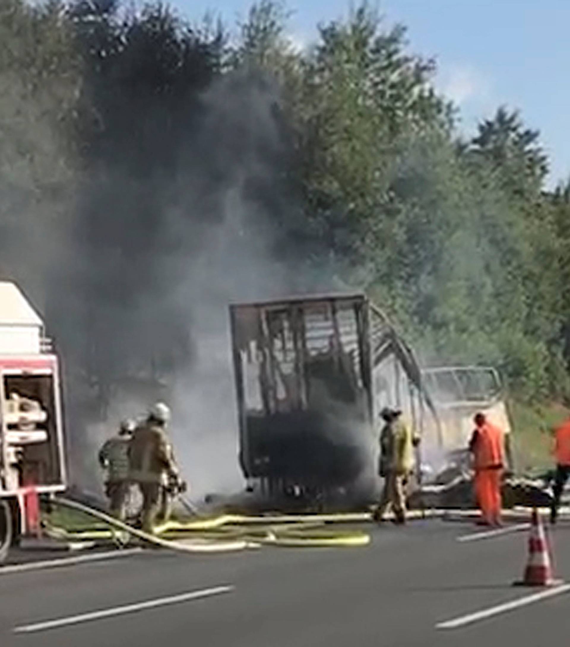 Firefighters walk at the site where a coach burst into flames after colliding with a lorry on a motorway near Muenchberg
