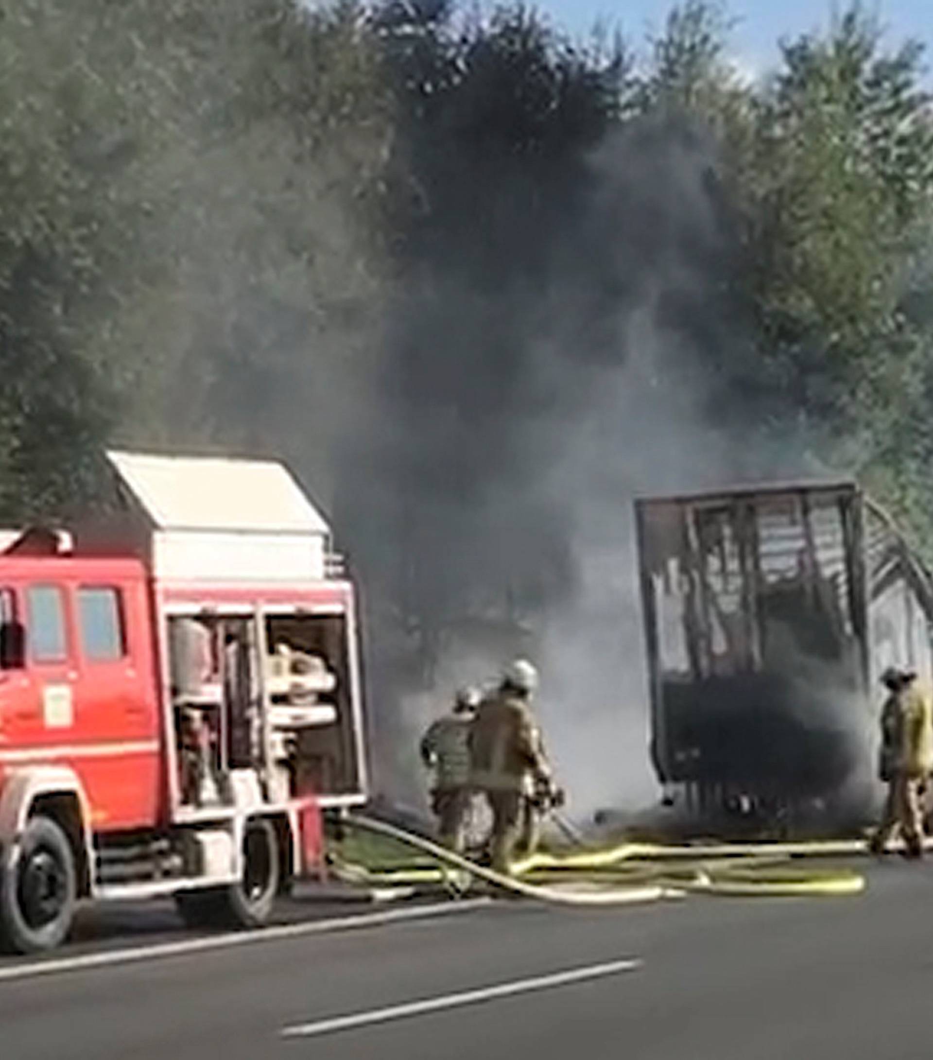 Firefighters walk at the site where a coach burst into flames after colliding with a lorry on a motorway near Muenchberg