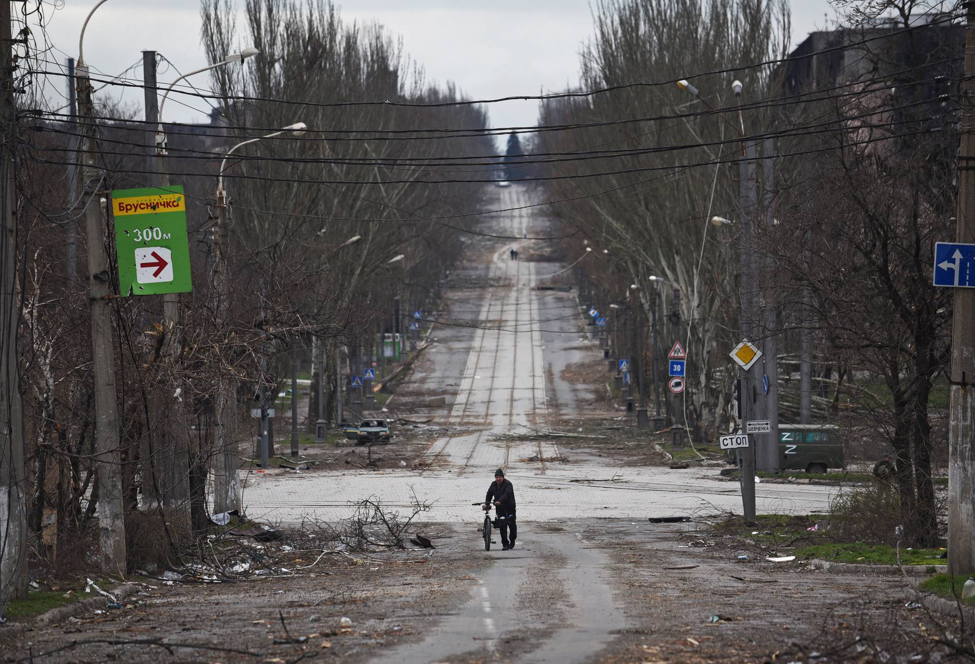 A local resident walks with a bicycle along a street in Mariupol