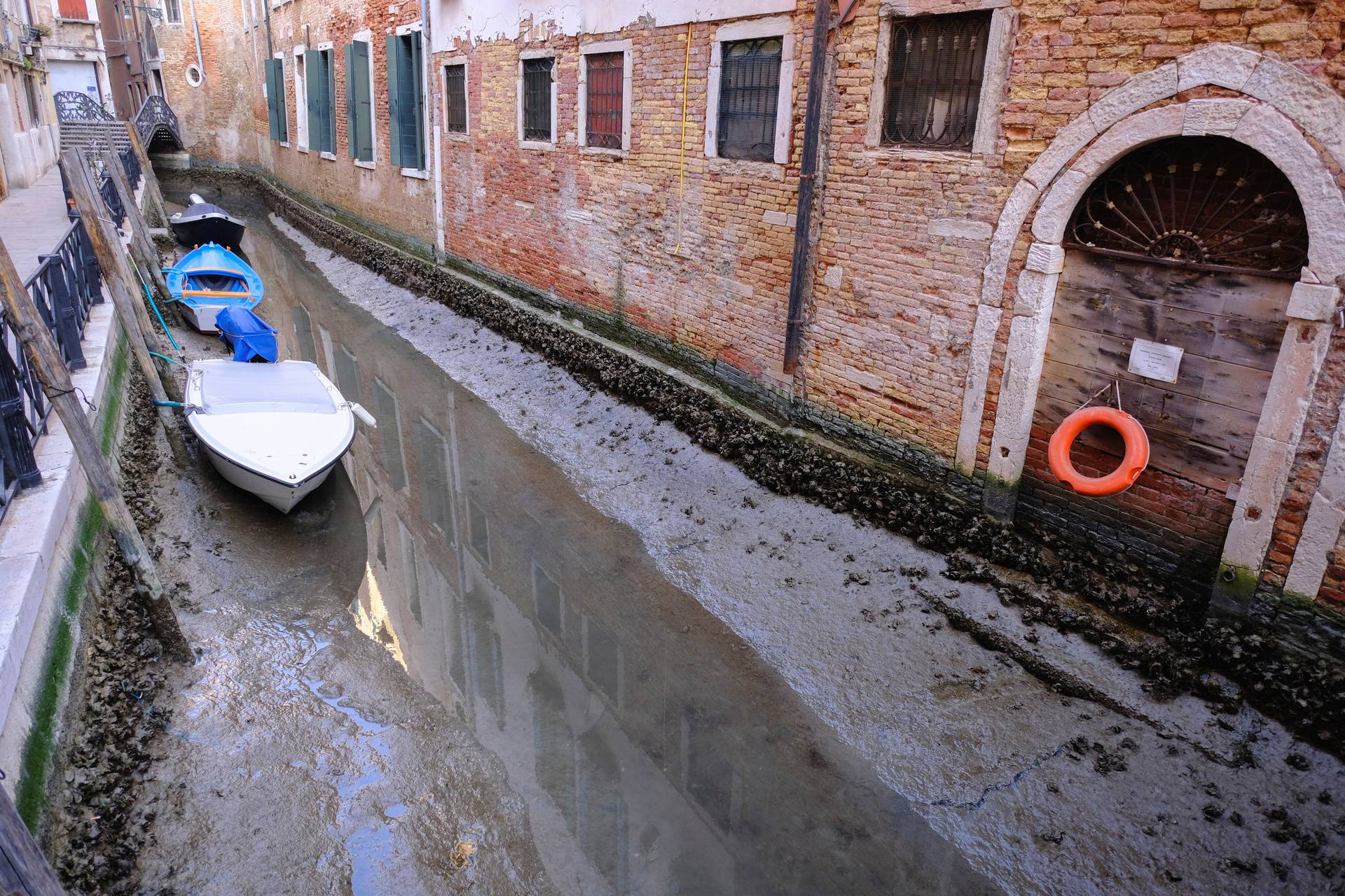 Boats are seen in a canal during an exceptionally low tide in the lagoon city of Venice