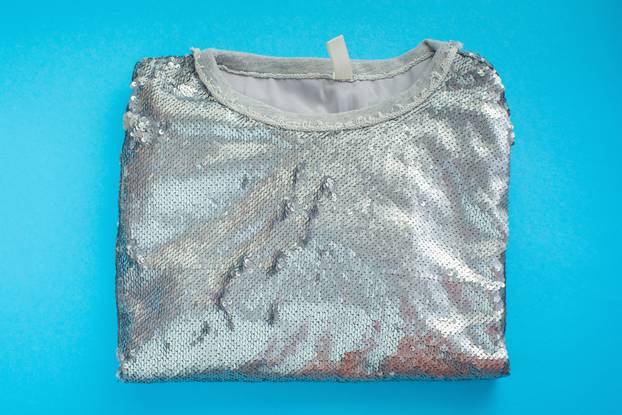 Women's elegant sweatshirt lies on a blue background top view Shiny texture decor sequins fashion