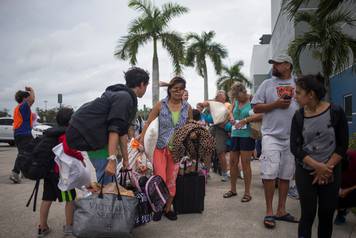 Residents carry their belongings into a shelter ahead of the downfall of Hurricane Irma in Estero, Florida