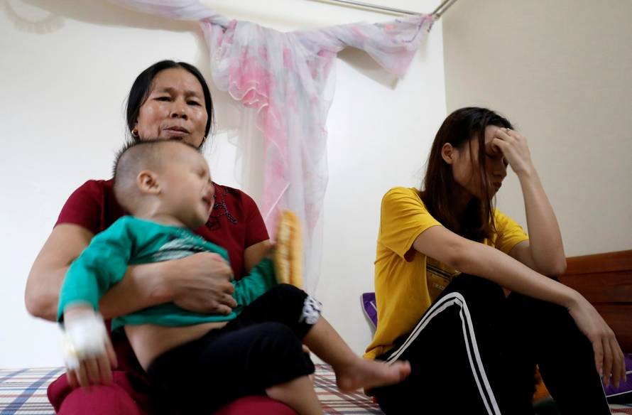 Hoang Thi Thuong, wife of Nguyen Dinh Tu, a Vietnamese suspected to be among dead victims found in a lorry in Britain, cries as her mother holds her son Nguyen Dinh Dan at their home in Nghe An province