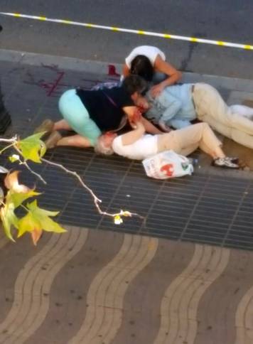 People attend to injured persons at the scene after a van crashed into pedestrians near the Las Ramblas avenue in central Barcelona