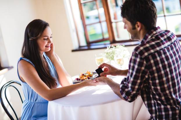 Young man proposing to woman in a restaurant