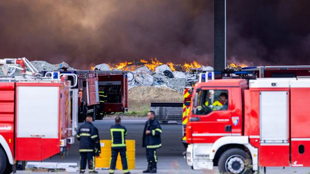 Firefighters stand near the fire at Drava International factory near Osijek