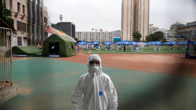 Security staff in a personal protection suit approaches the photographer at a testing site at the Guangan Sport Center after an unexpected spike of cases of the coronavirus disease (COVID-19) in Beijing