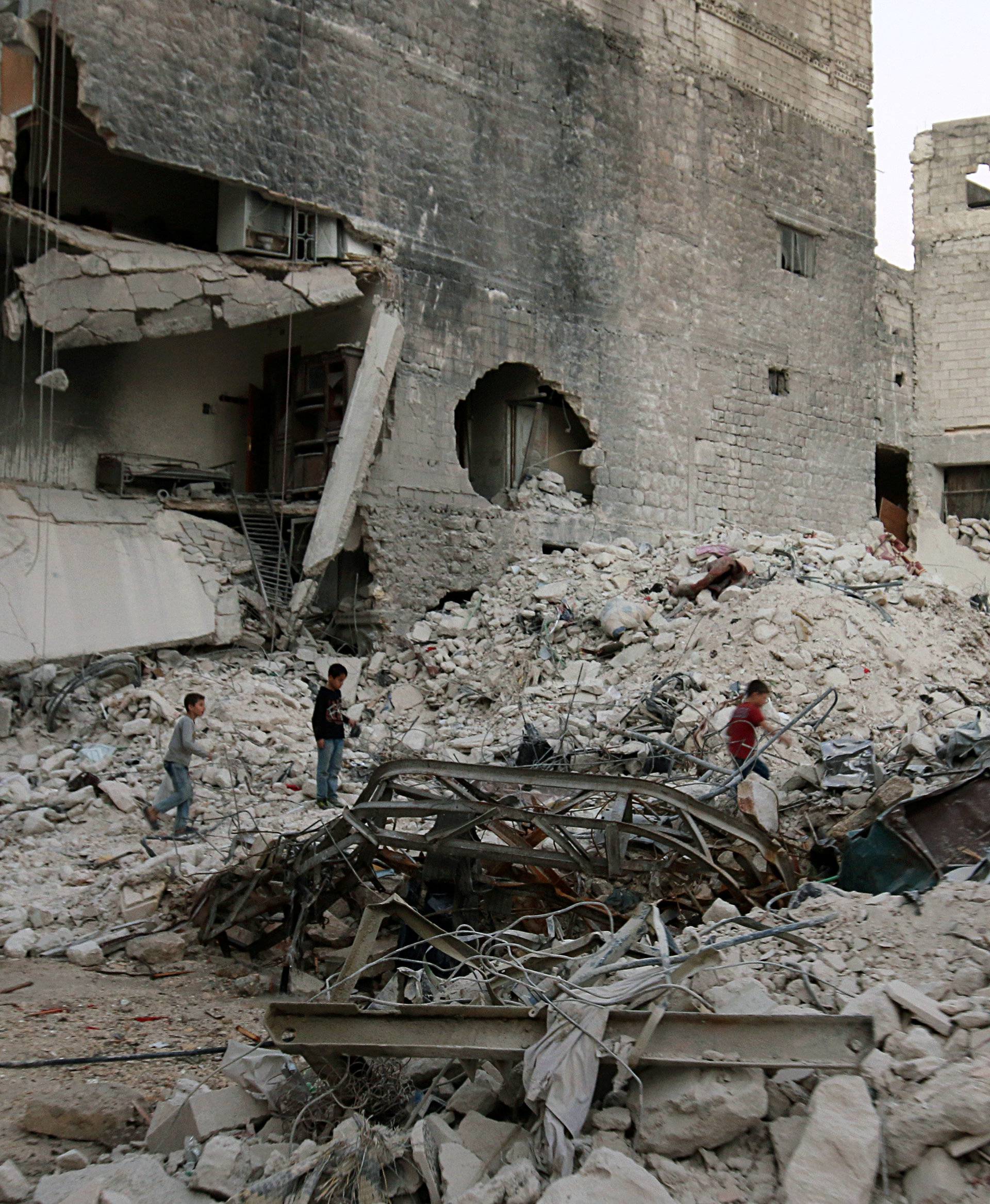 Boys make their way through the rubble of damaged buildings in the rebel held area of al-Kalaseh neighbourhood of Aleppo