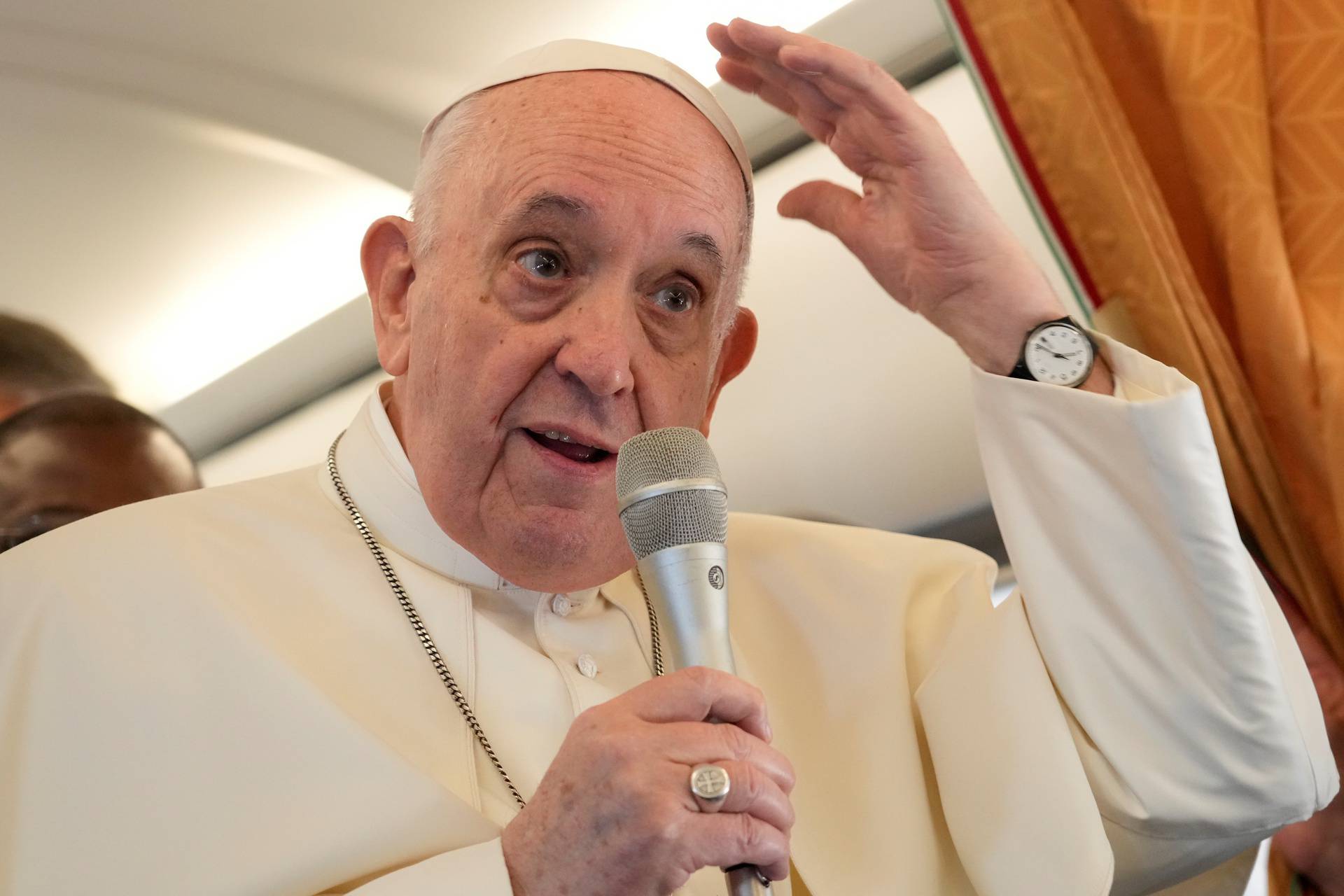 Pope Francis greets journalists aboard an airplane on his way to Hungary