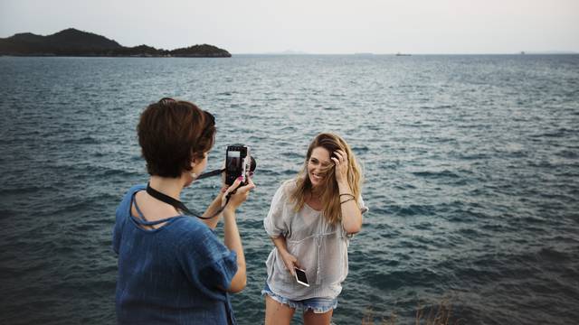 Women taking photo by seashore