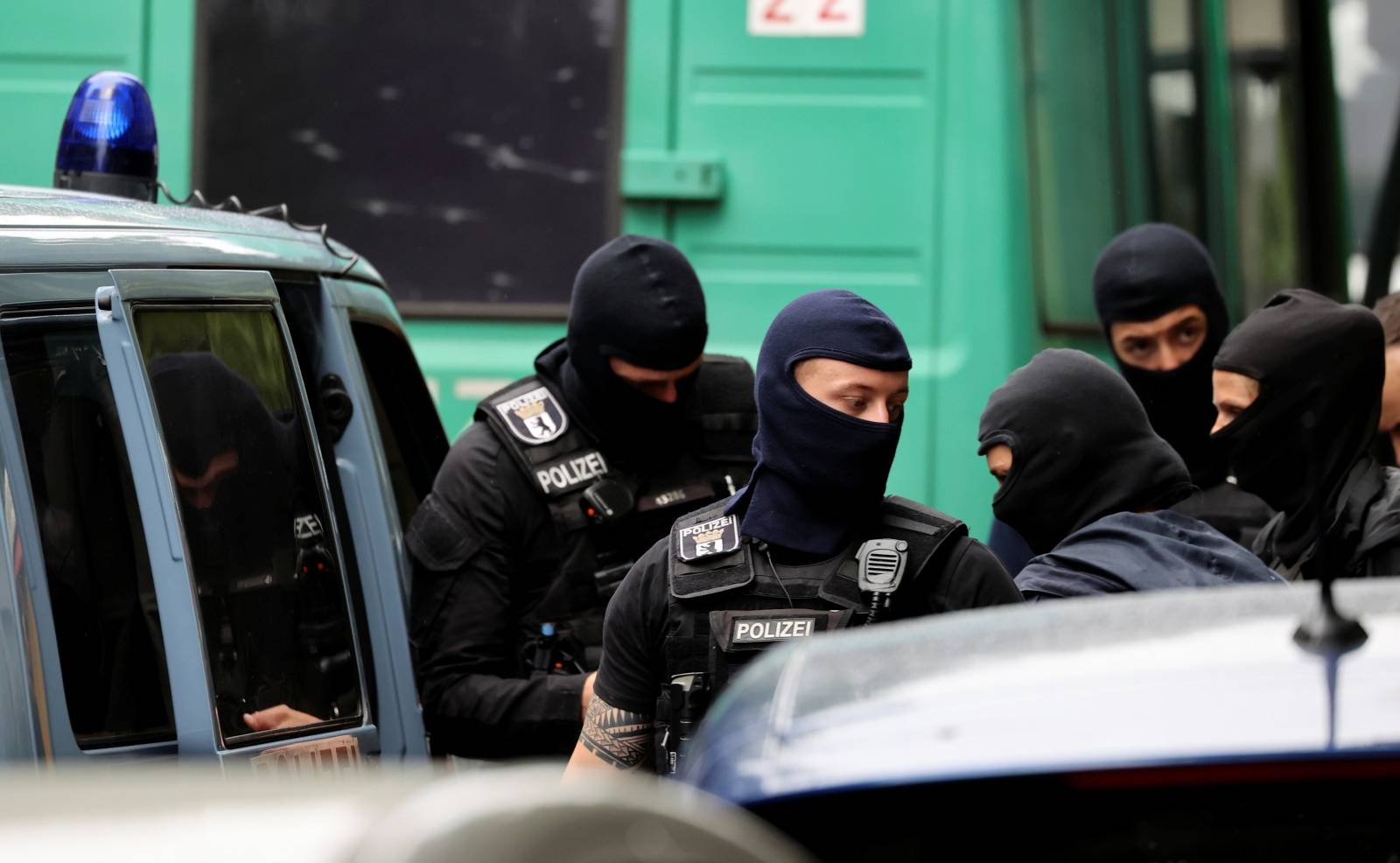 Police officers gather outside during a raid in an apartment building at Kreuzberg district in Berlin