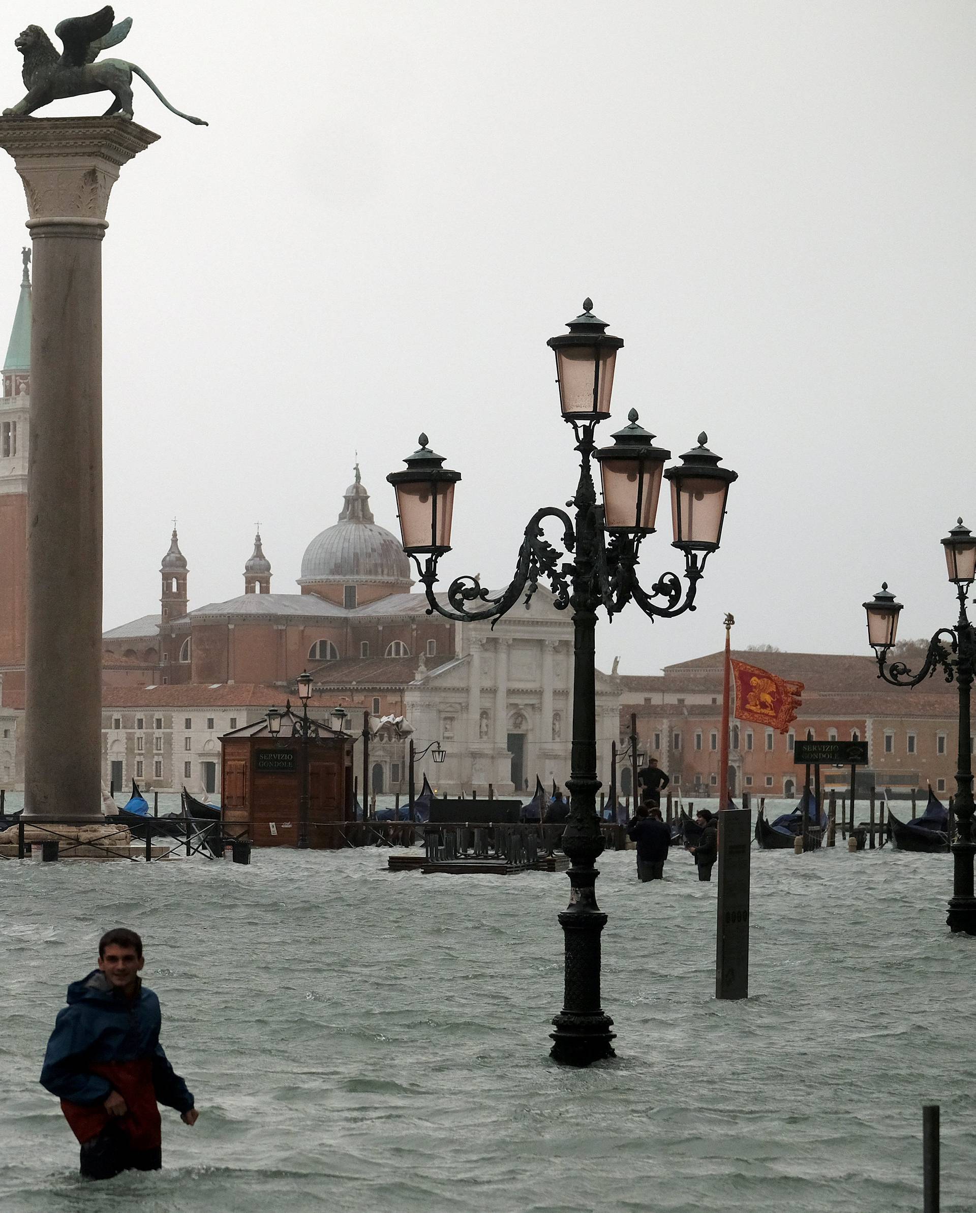 People walk in flooded Saint Mark Square during a period of seasonal high water in Venice