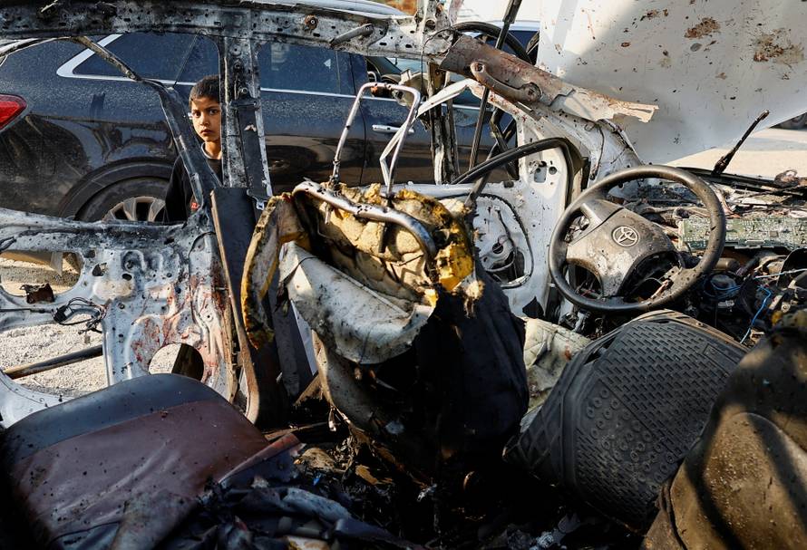 Palestinians inspect the site of an Israeli airstrike targeting a police vehicle in the central Gaza Strip
