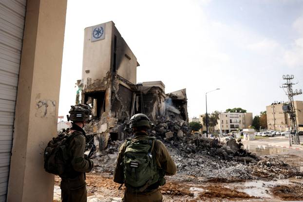 Israeli soldiers look at the remains of a police station following a mass infiltration by Hamas gunmen from the Gaza Strip, in Sderot