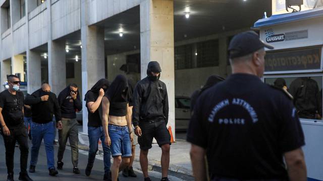 Police escort soccer fans to the police station in Athens