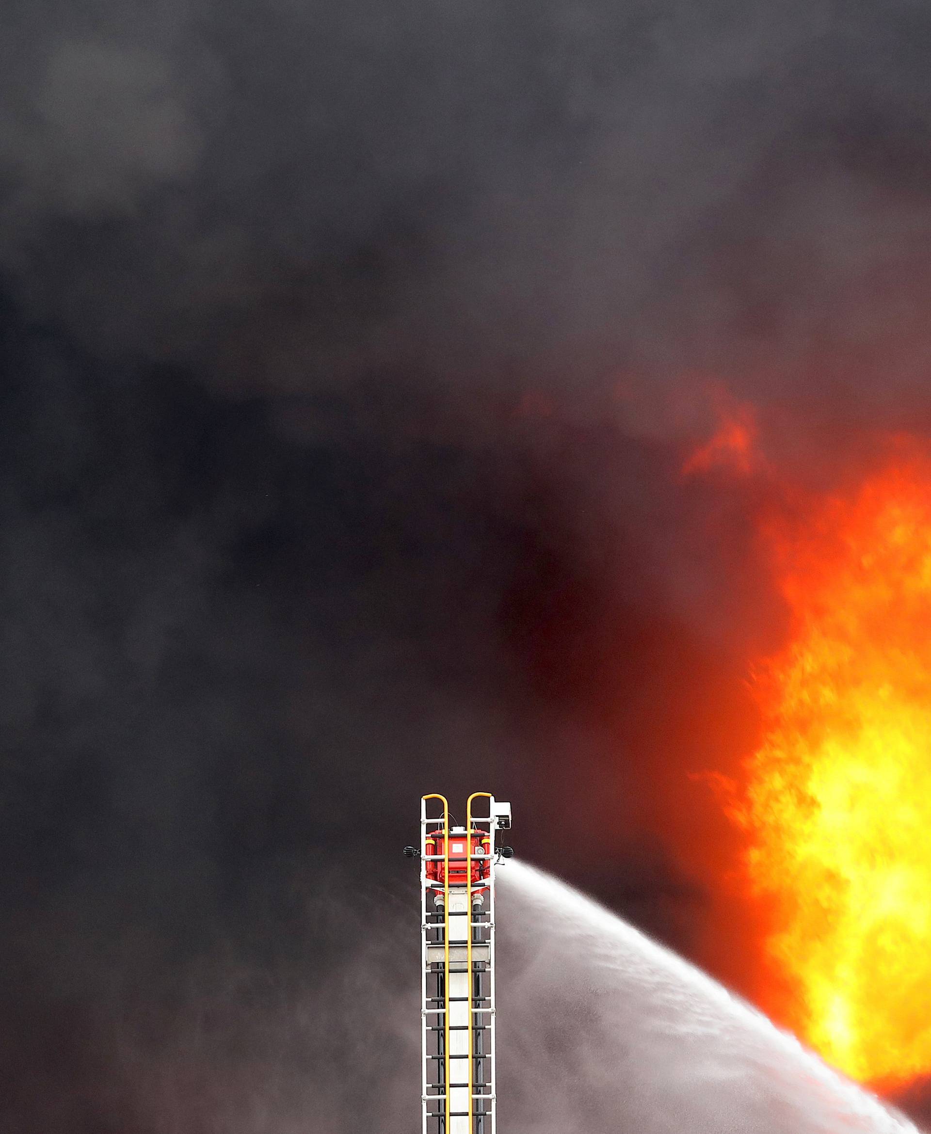 Fire crews operate a hose attached to a ladder at a fire in a factory in Melbourne