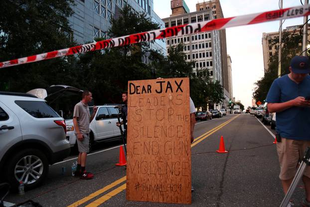 A man holds a sign in support of gun control outside of The Jacksonville Landing after a shooting in Jacksonville