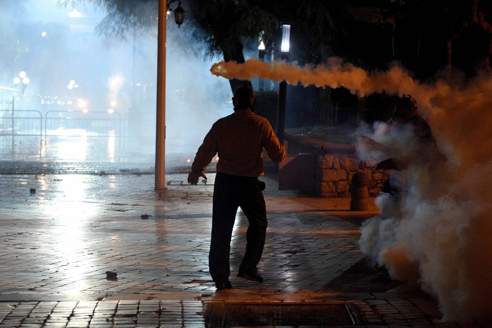 A protester is pictured thru tear gas in front of Parliament in Tirana, Albania