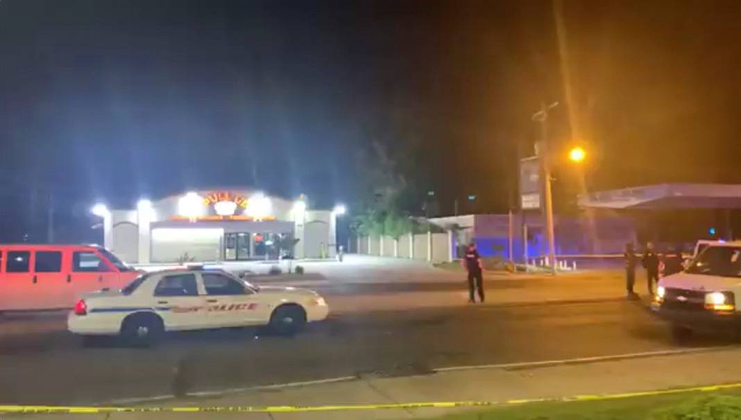 Police personnel and their vehicles are seen near the scene in the aftermath of a drive-by shooting at a liquor store in Shreveport, Louisiana