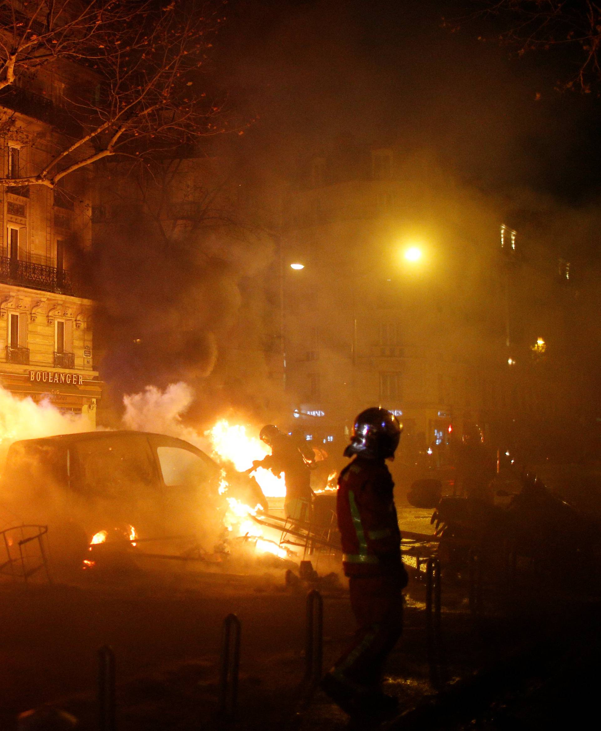 Firemen extinguish burning cars set afire by protesters wearing yellow vests, a symbol of a French drivers' protest against higher diesel fuel taxes, during clashes near the Place de l'Etoile in Paris