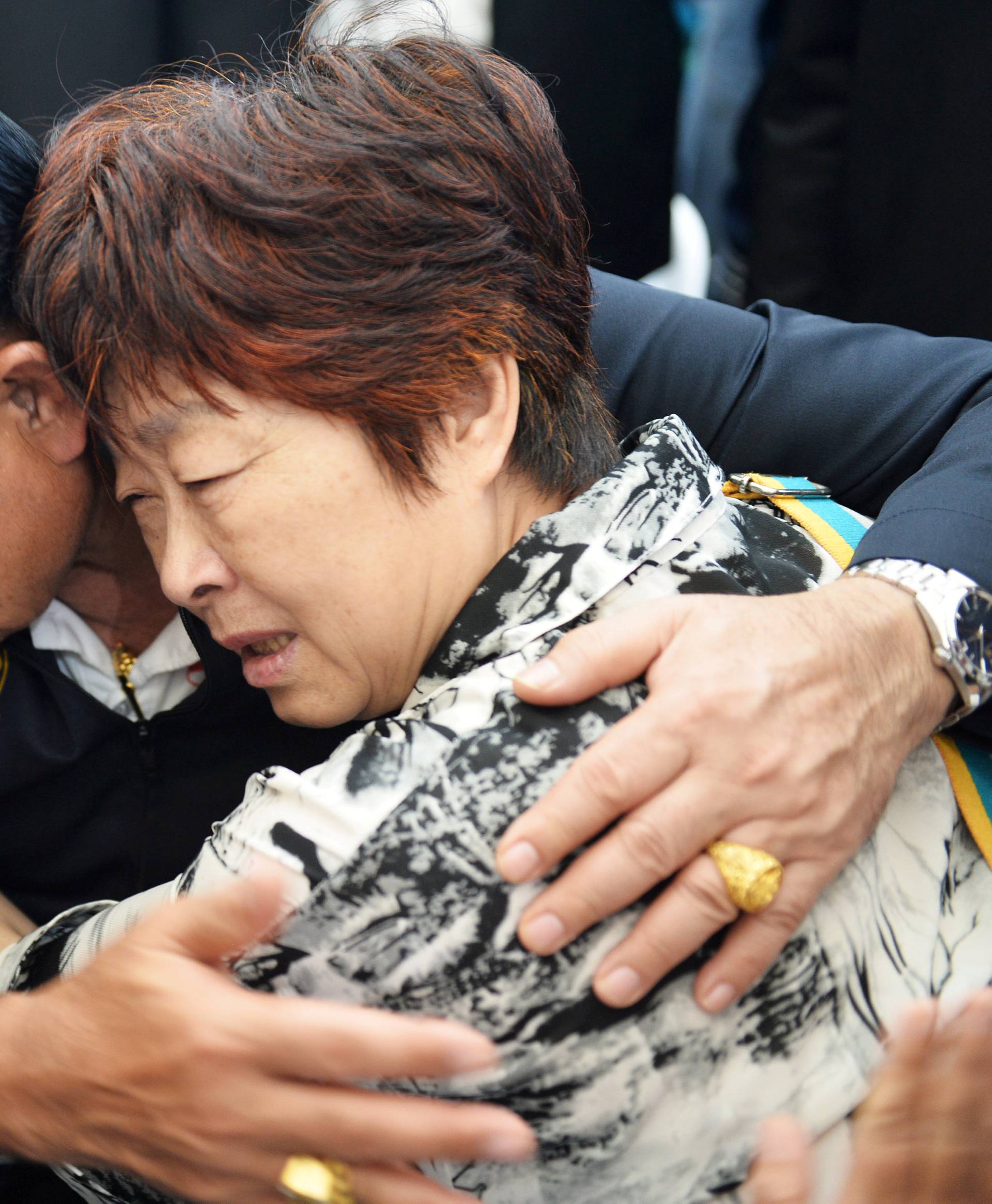 Thailand's Prime Minister Prayuth Chan-ocha comforts a relative of Chinese tourists involved in a sunken tourist boat accident at a hospital in Phuket