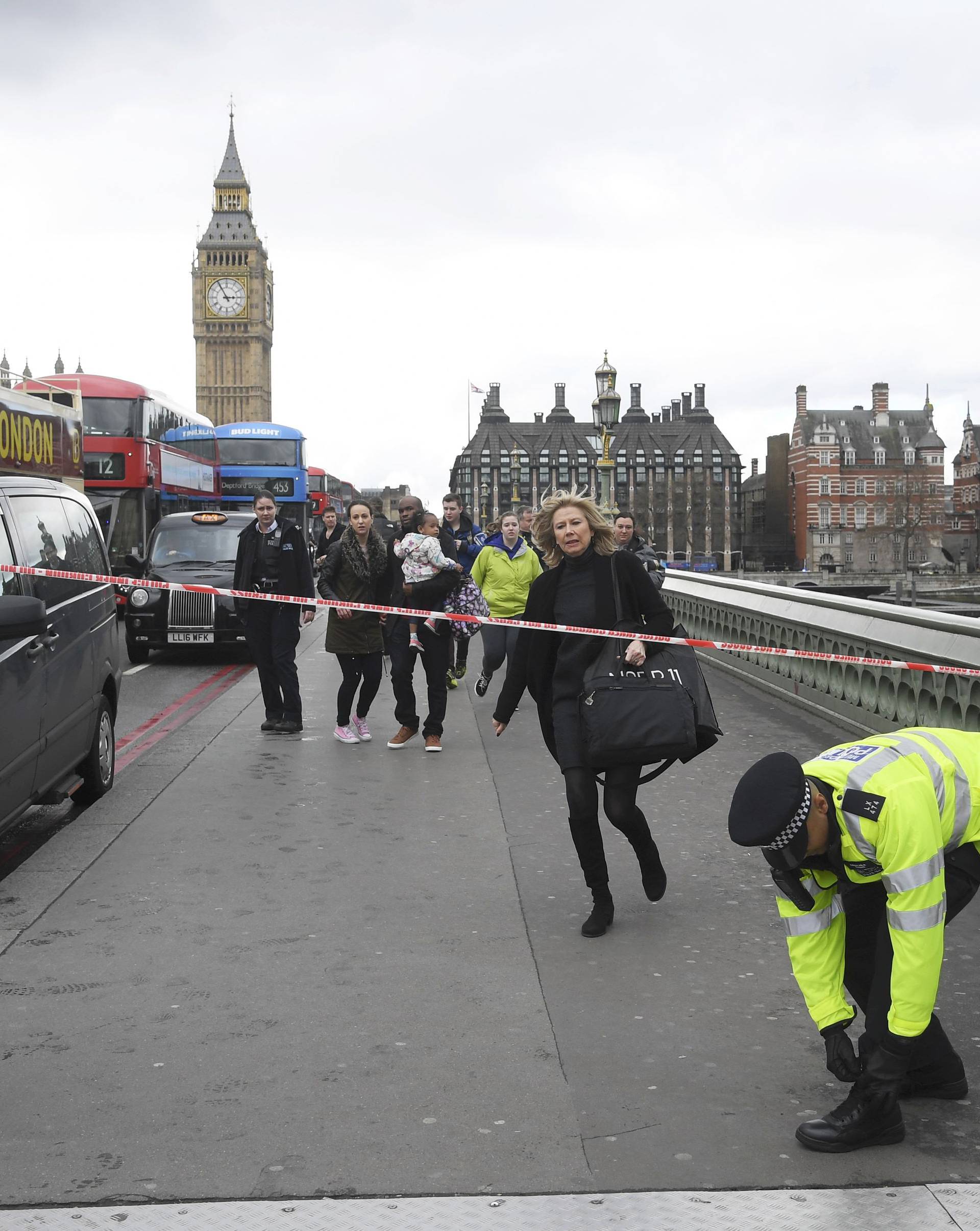 A woman ducks under a police tape after an incident on Westminster Bridge in London