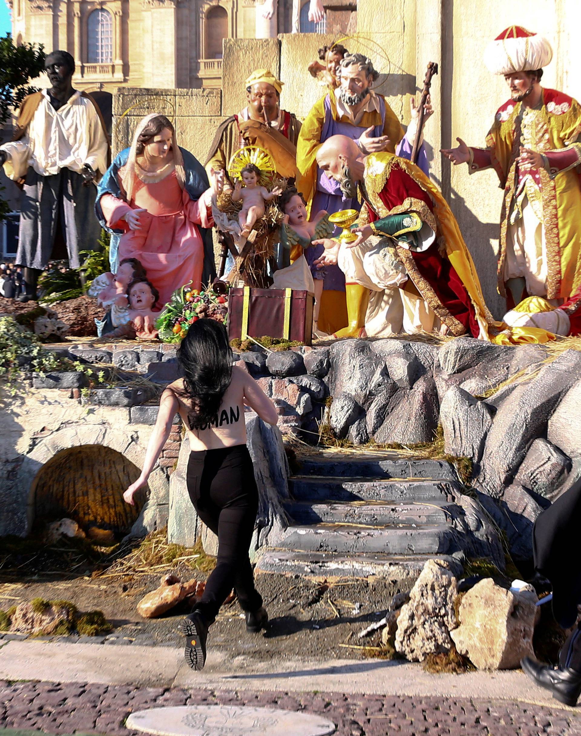 A Vatican gendarme attempts to block a topless activist of women's rights group Femen, who tries to reach the Nativity scene in Saint Peter's square in the Vatican