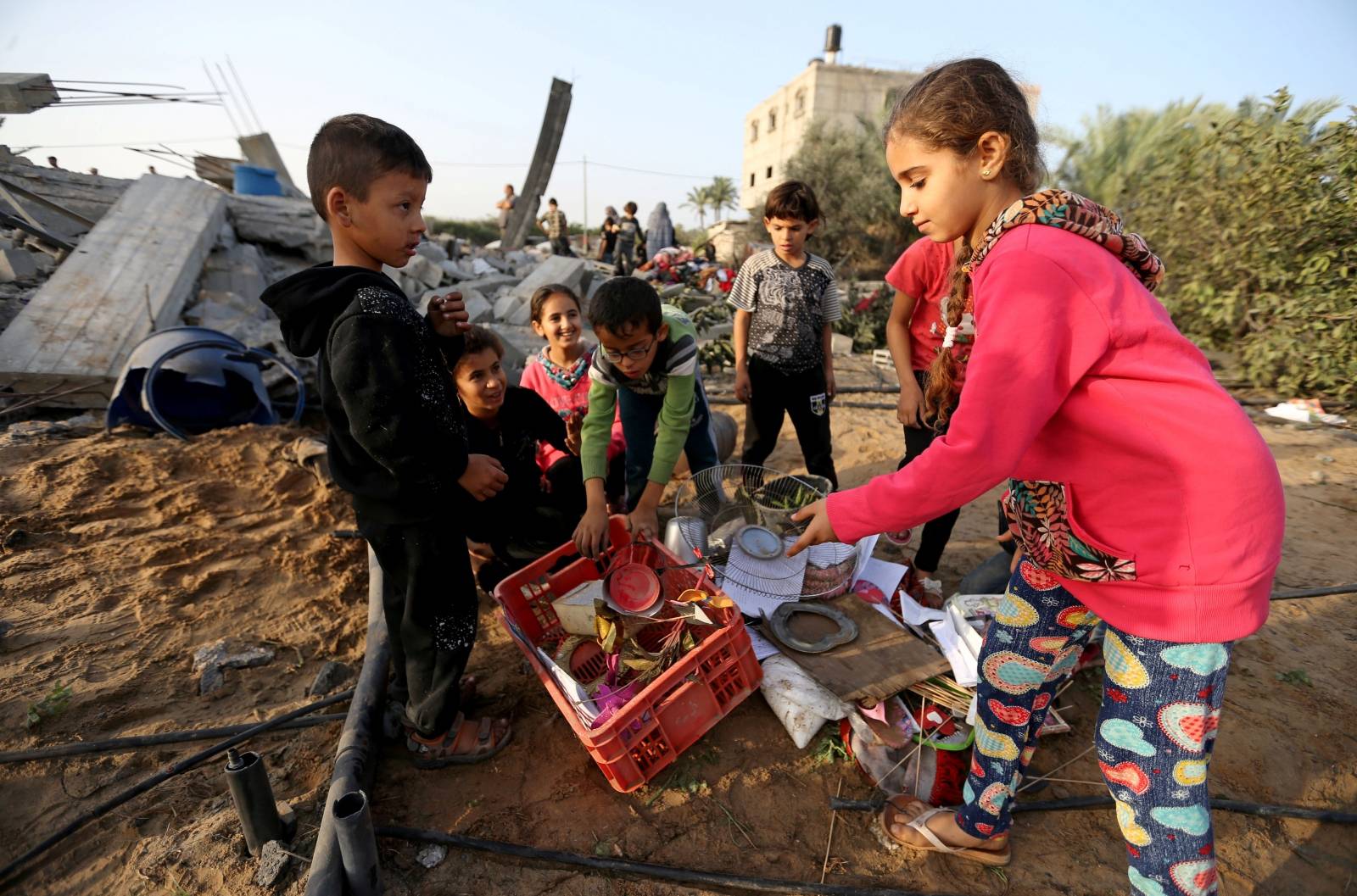 Palestinian children collect objects from a house destroyed in an Israeli air strike in the southern Gaza Strip