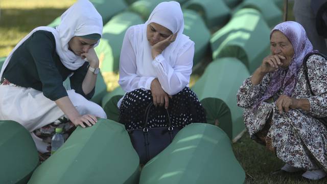 Women cry near coffins of their relatives, who are newly identified victims of the 1995 Srebrenica massacre, which are lined up for a joint burial in Potocari near Srebrenica