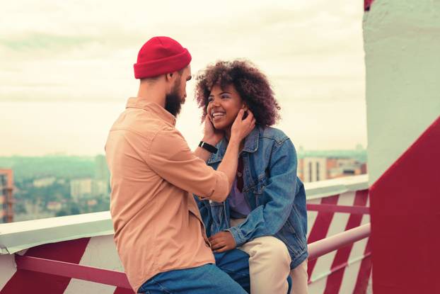 Loving man touching the face of his smiling girlfriend and looking at her