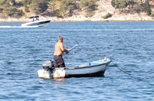 Šibenik: Ribolovac  u brodi?u po najja?em suncu.