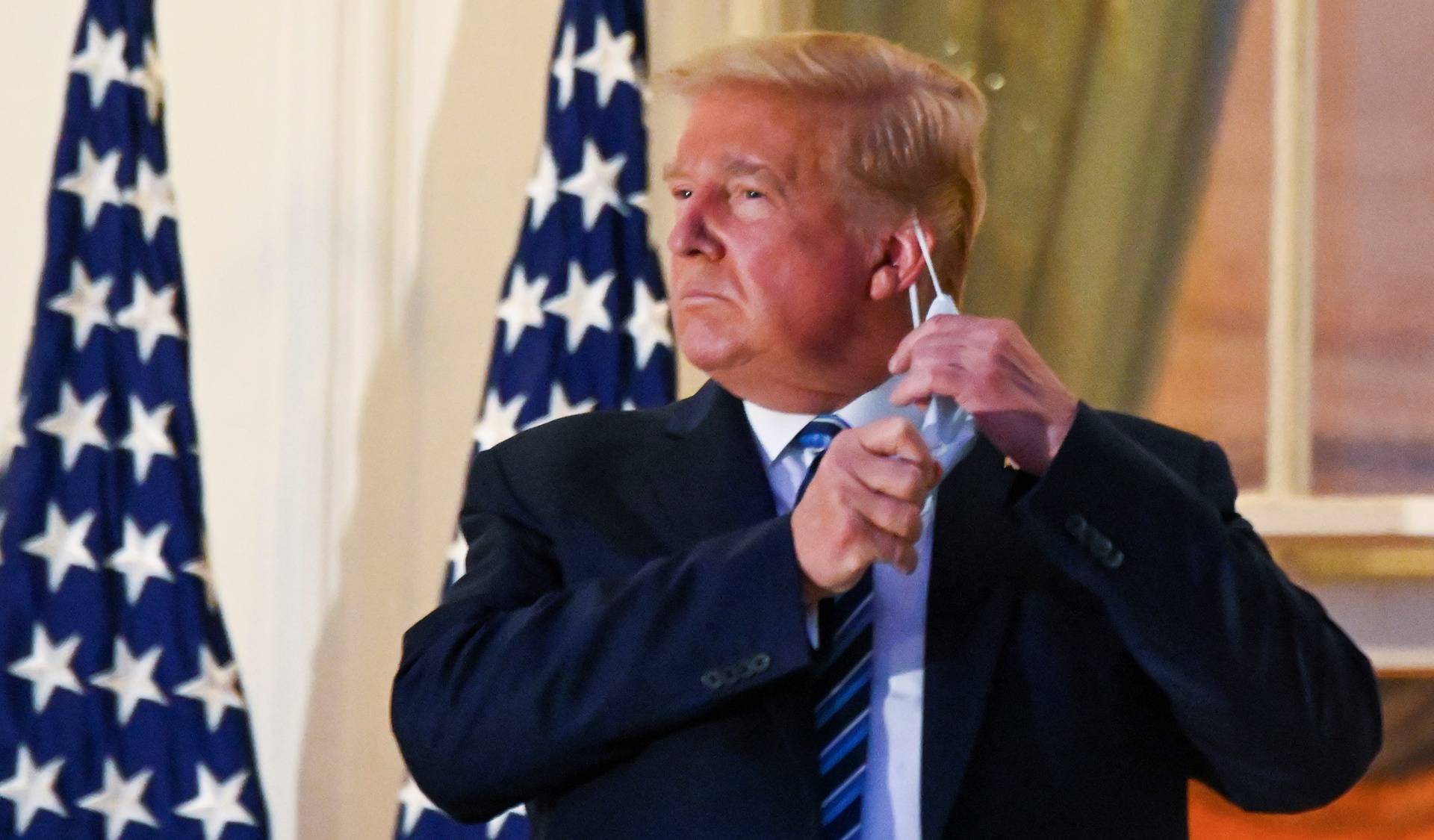 U.S. President Donald Trump pulls off his face mask as he returns to the White House after being hospitalized at Walter Reed Medical Center for coronavirus disease (COVID-19), in Washington
