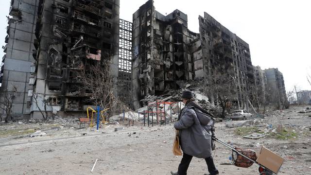A local resident walks near a destroyed apartment building in Mariupol