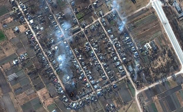 A satellite image shows burning homes and impact craters in fields, near Rivnopillya
