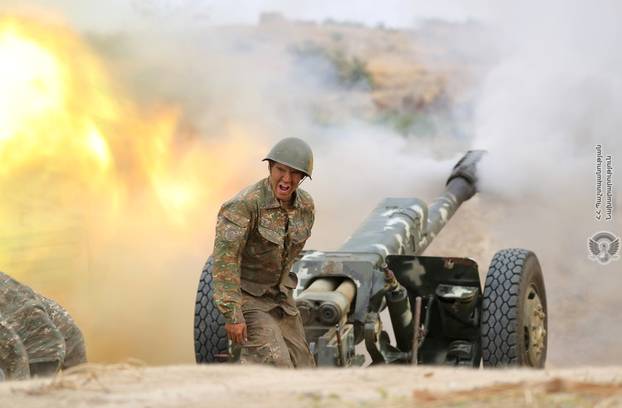 An ethnic Armenian soldier fires an artillery piece during fighting with Azerbaijan