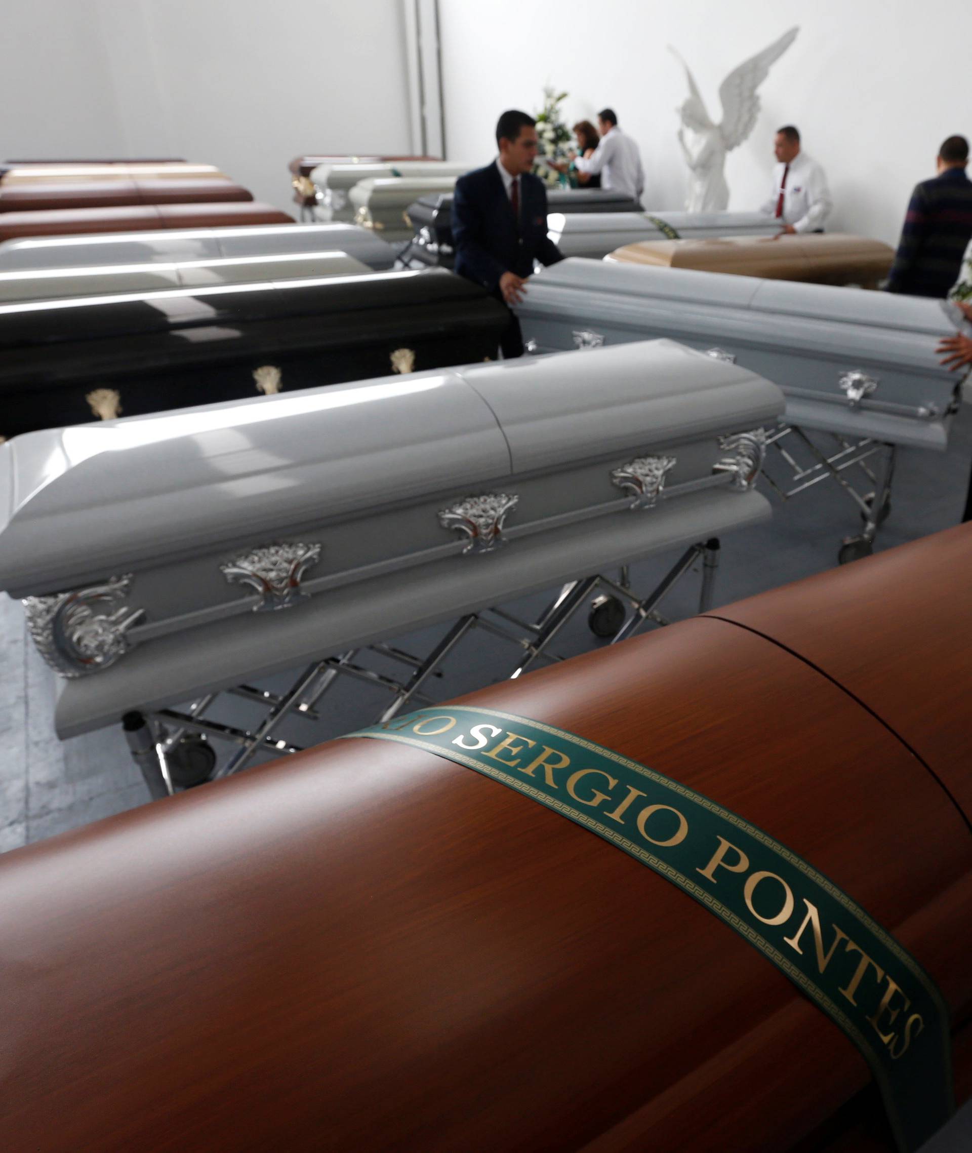 Funeral workers arrange coffins near the coffin holding the remains of Pontes who died along with others in an accident of the plane that crashed into the Colombian jungle with Brazilian soccer team Chapecoense onboard, in Medellin