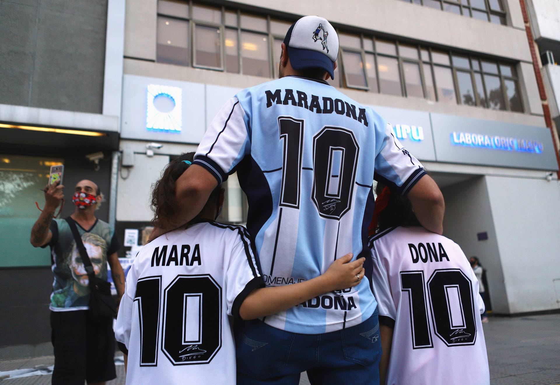 Fans of Argentine soccer great Diego Maradona pose for a photograph outside the clinic where Maradona underwent brain surgery, in Olivos