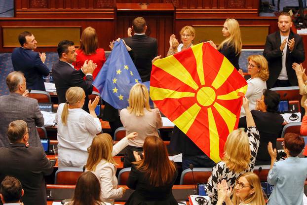 North Macedonia's SDSM party members of Parliament hold EU and Macedonian flags during debate on a French-brokered deal, in Skopje