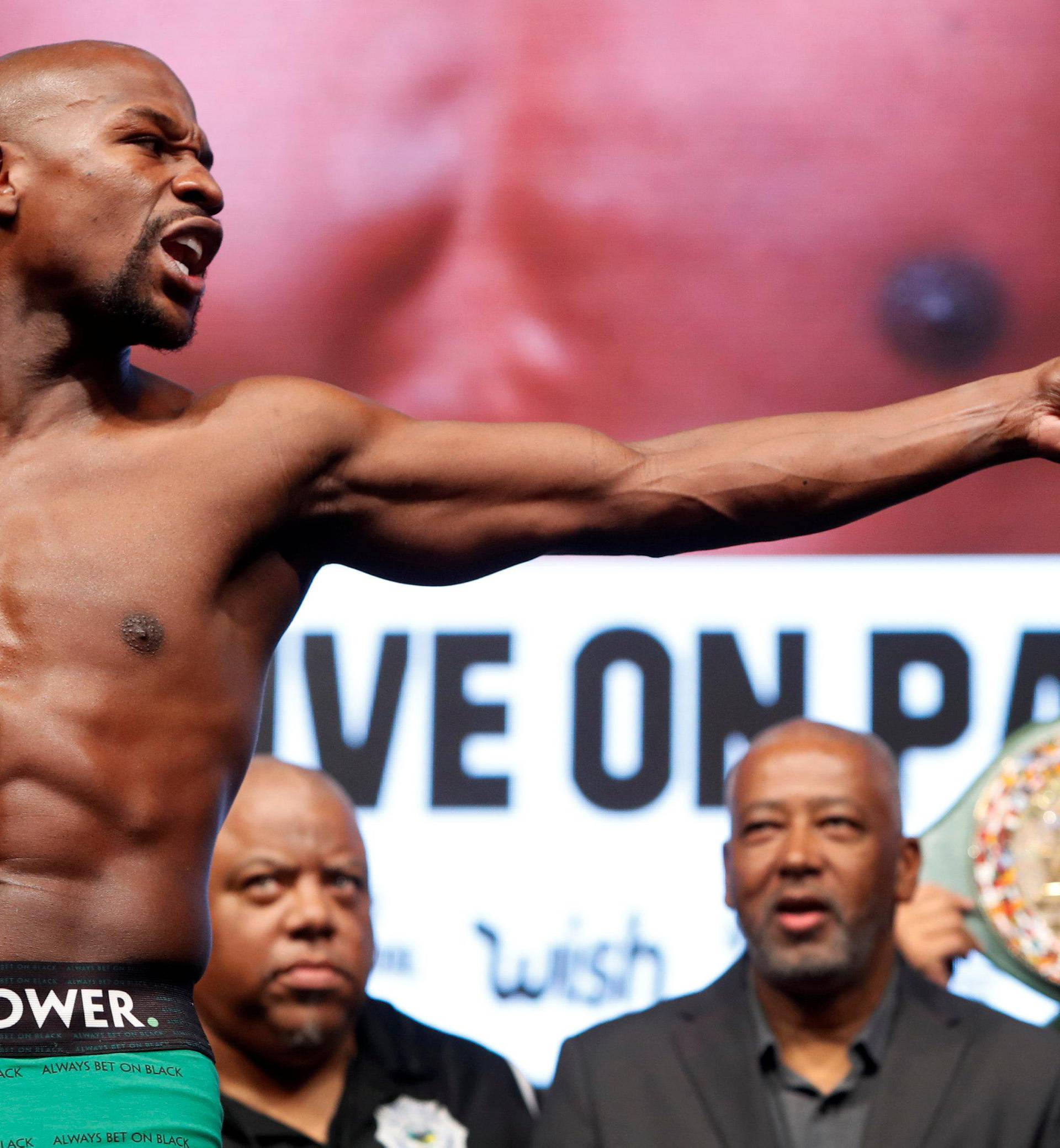 Undefeated boxer Floyd Mayweather Jr. of the U.S. points to UFC lightweight champion Conor McGregor of Ireland  during his official weigh-in at T-Mobile Arena in Las Vegas