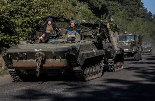 Ukrainian servicemen ride an armoured personnel carrier near the Russian border in Sumy region